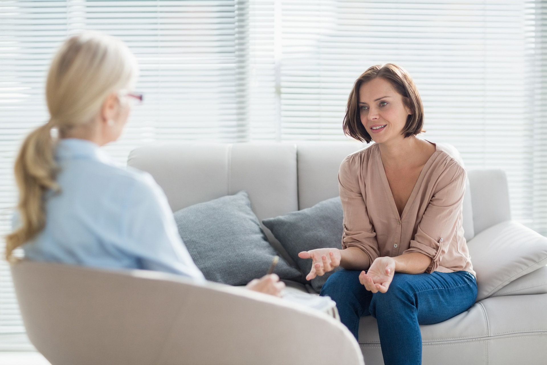 woman talking on couch across from doctor with clipboard