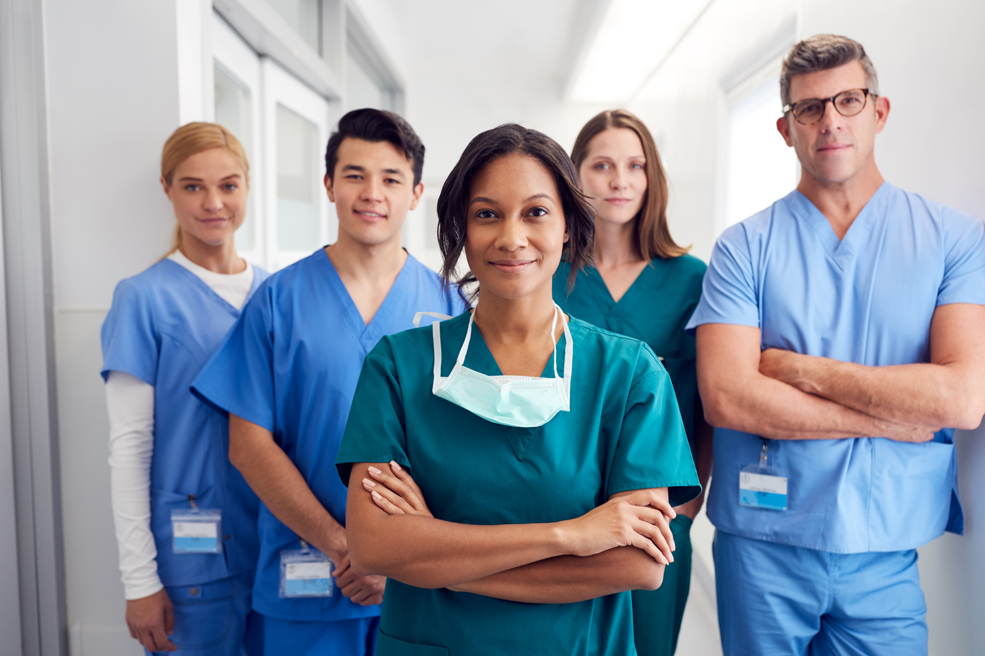 five smiling nurses in blue scrubs